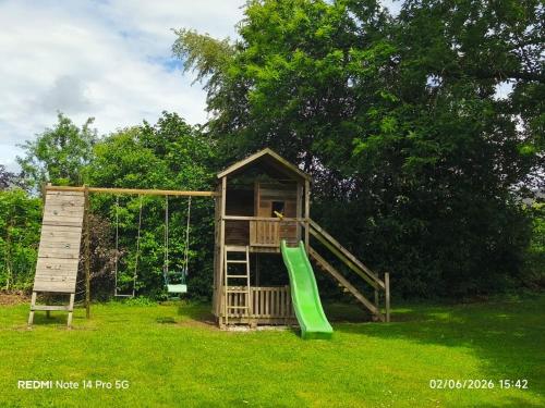 a playground with a green slide and a swing at Le gîte d’Hayen in Sprimont