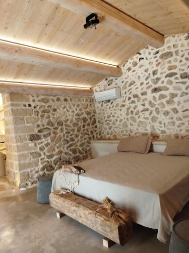 a bedroom with a bed and a stone wall at Masseria Petra in Martano