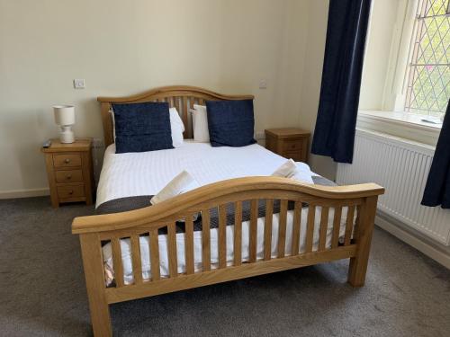 a bedroom with a wooden bed with blue pillows at St Nicholas Hotel Shrewsbury in Shrewsbury
