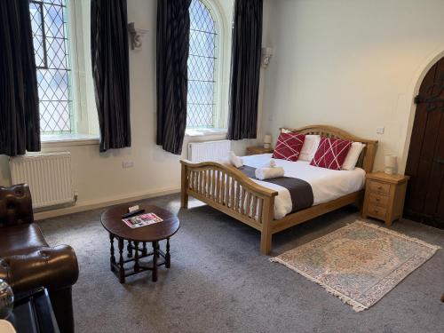a bedroom with a bed and a table and windows at St Nicholas Hotel Shrewsbury in Shrewsbury