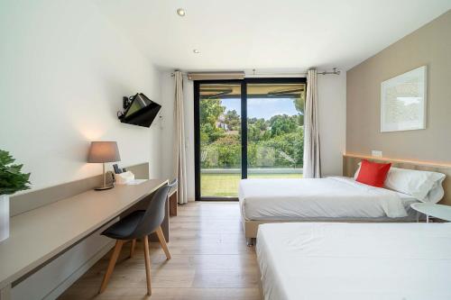 a hotel room with two beds and a desk and a window at Villa SP1 Suites Santa Ponsa by Sealand Villas in Santa Ponsa