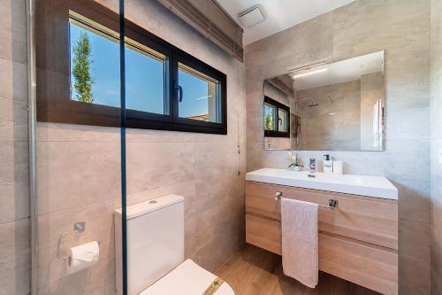 a bathroom with a toilet and a sink and a window at Villa SP1 Suites Santa Ponsa by Sealand Villas in Santa Ponsa