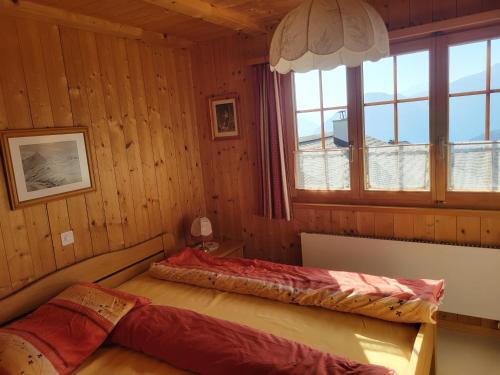 a bedroom with a bed in a room with wooden walls at Chalet Heinzenberg in Urmein