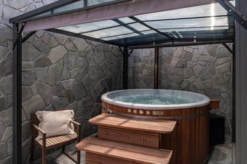 a hot tub with a pergola and a chair at JW Apartments in Krościenko