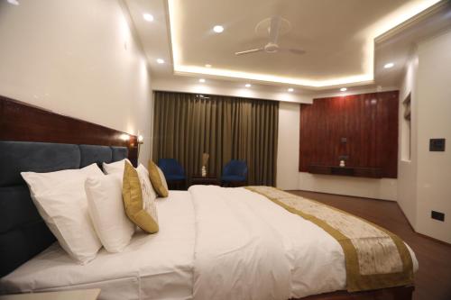 a bedroom with a large bed with white sheets and yellow pillows at The Pamir Hotel in Nubra