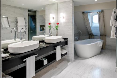 a bathroom with two sinks and a bath tub at Hotel Schweizerhof Bern & Spa in Bern