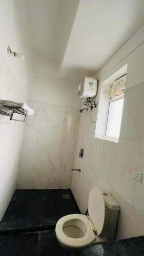 a small bathroom with a toilet and a window at The Comfort stays gomti nagar in Lucknow