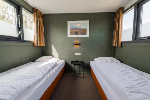 two beds in a room with two windows at 't Eibernest in De Cocksdorp