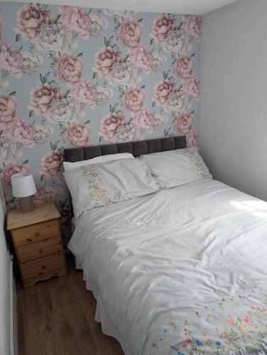 a bedroom with a bed with pink roses wallpaper at The Lighthouse Chalet in Leysdown-on-Sea