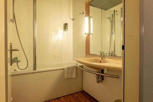 a bathroom with a sink and a shower and a tub at a&o Hostel Milano Ca Granda in Milan