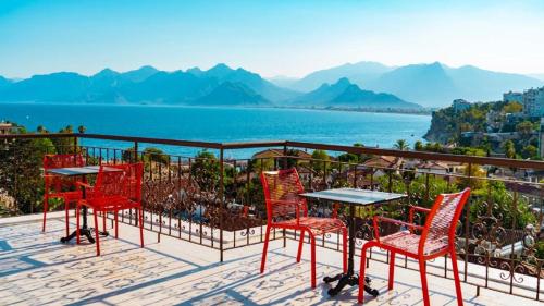 a group of red chairs and tables on a patio overlooking the water at Patron Hotel in Antalya