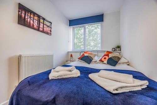 a bedroom with a blue bed with towels on it at Stylish Flat in the City Centre - Pass the Keys in Portsmouth