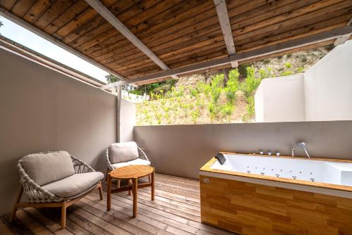 a bathroom with a tub and a chair at Bamboo Suites Hotel - Adults Only in Ialysos
