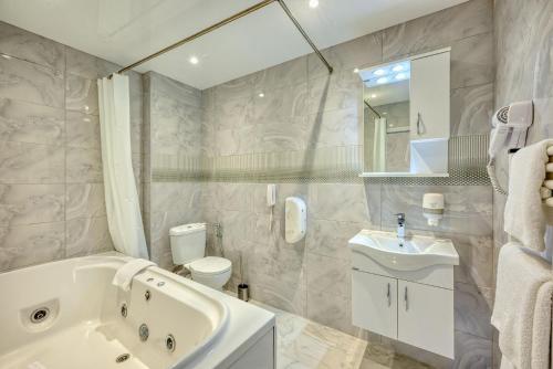 ein Badezimmer mit Badewanne, Toilette und Waschbecken in der Unterkunft Augusta SPA Hotel in Chissarja