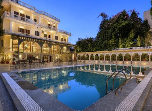 a hotel with a swimming pool in front of a building at The Amar Mahal Luxury Heritage Hotel Near Fateh Sagar Lake, Udaipur in Udaipur