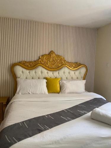 a bed with a gold and white headboard and pillows at Shikaz Homes 2 Bedroom Near Jkia Airport in Nairobi