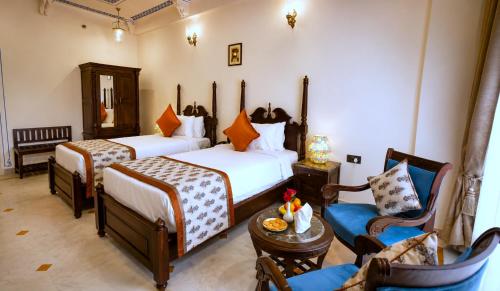 a hotel room with two beds and a chair at The Amar Mahal Luxury Heritage Hotel Near Fateh Sagar Lake, Udaipur in Udaipur