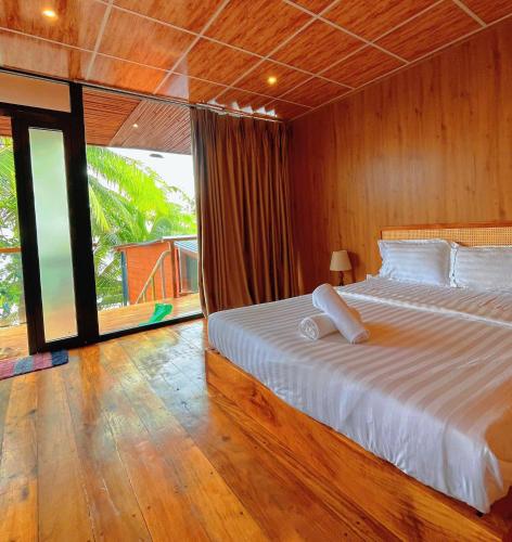 a bedroom with a large bed and a large window at Waikiki Lagi Beach in Ấp Tam Tân
