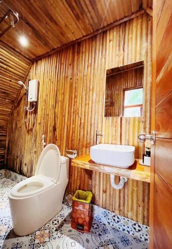 a wooden bathroom with a toilet and a sink at Waikiki Lagi Beach in Ấp Tam Tân