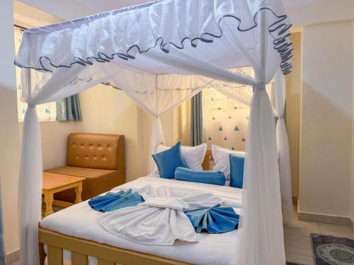 ein Schlafzimmer mit Himmelbett und blauen Kissen in der Unterkunft Miriito's Hotel in Kisii