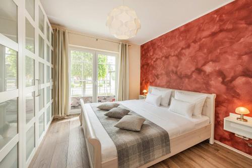 a bedroom with a large bed with a red wall at Ferienwohnung Auszeit am Meer in Koserow