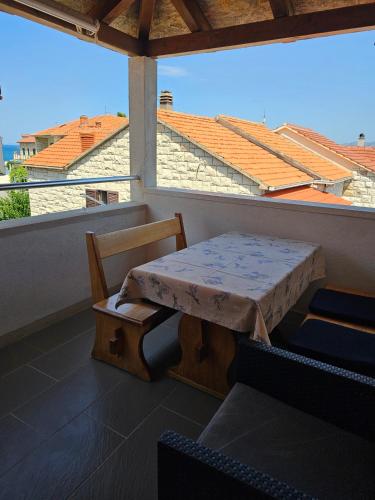 a table and chair on a balcony with a view at Apartmani Banić Apartman 4 in Postira