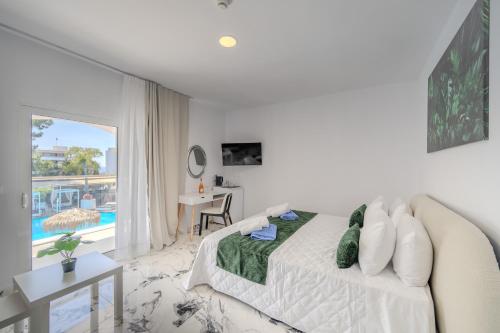a white bedroom with a bed and a view of a pool at Bamboo Suites Hotel - Adults Only in Ialysos
