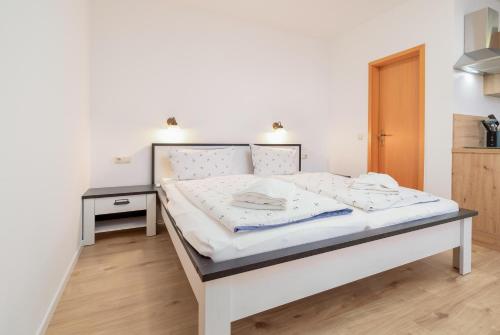 a bedroom with a white bed with a night stand at Meeresbrise in Thiessow