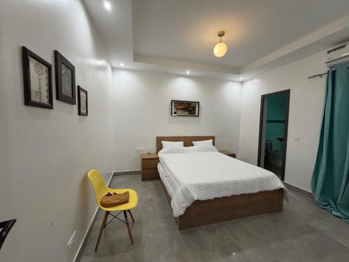 a bedroom with a bed and a yellow chair at Le Welcome Almadies in Ngor