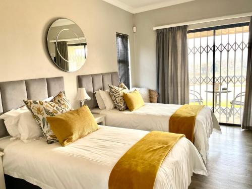 a hotel room with two beds and a mirror at C’est La Vie in Balgowan