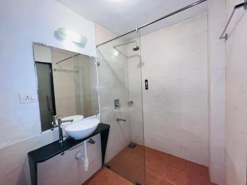 a bathroom with a sink and a glass shower at Baga Central Studio Apartment in Baga