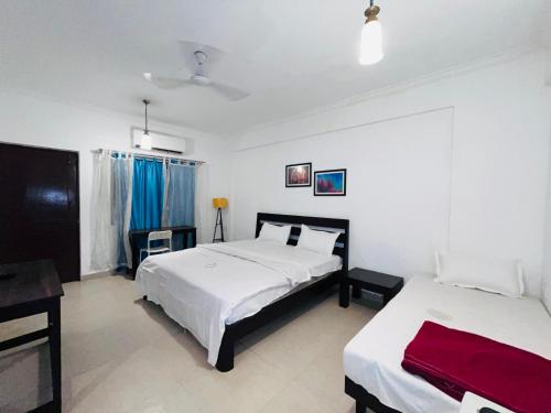 a hotel room with two beds and a desk at Baga Central Studio Apartment in Baga