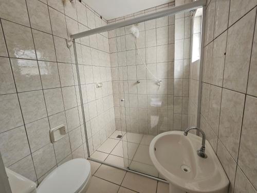 a white bathroom with a toilet and a sink at Ok Inn Hotel Express in Tubarão