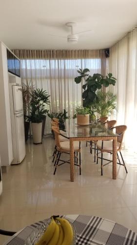 a dining room with a table and chairs and plants at confortável suite no jardim Botânico in Ribeirão Preto