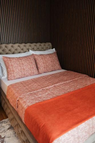 a large bed with orange and white sheets and pillows at Numero Uno LUX in Sombor