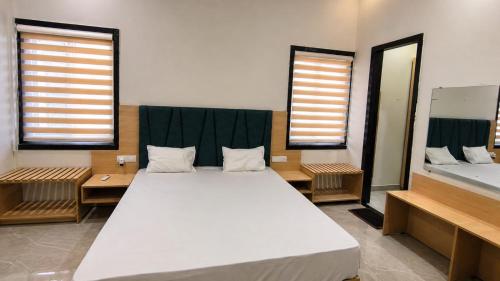 a large bed in a room with two windows at Harsh Pushp Garden in Raipur