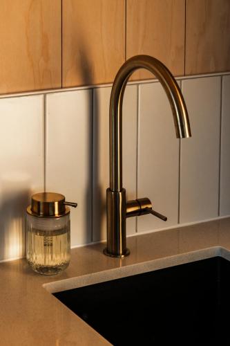 a kitchen sink with a faucet and a glass jar at Vineyard Cabins at Château Puynard in Berson