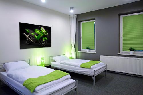 two beds in a room with a motorcycle on the wall at Greyhouse in Jaworzno
