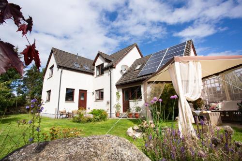 a house with solar panels on the roof at 5-Bed Highland Lodge - NC500 - Sleeps 10 in Alness