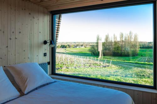 a bedroom with a large window looking out at a vineyard at Vineyard Cabins at Château Puynard in Berson