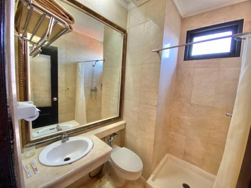 a bathroom with a sink and a toilet and a mirror at Quds Royal Hotel in Surabaya