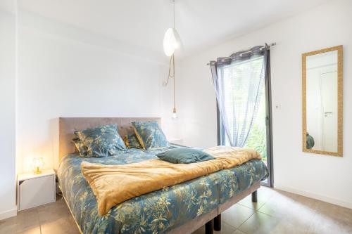 a bedroom with a bed with blue sheets and a mirror at Villa Les Lodges Terre et Mer in Concarneau
