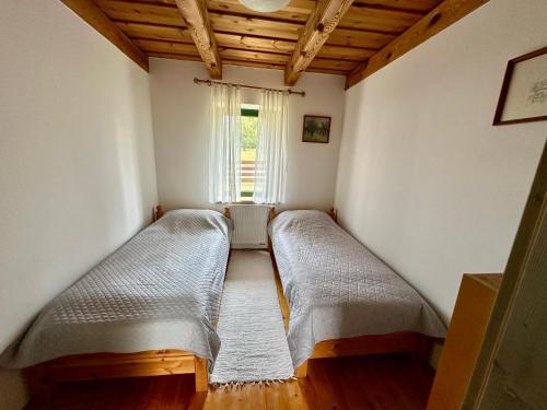 two beds in a room with a window at Apkó Vendégház in Őriszentpéter