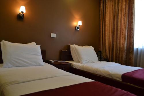two beds in a hotel room with lights on the wall at Hotel Super 8 in Skopje