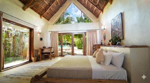 a bedroom with a bed and a large window at MONEA The Nest in Paje