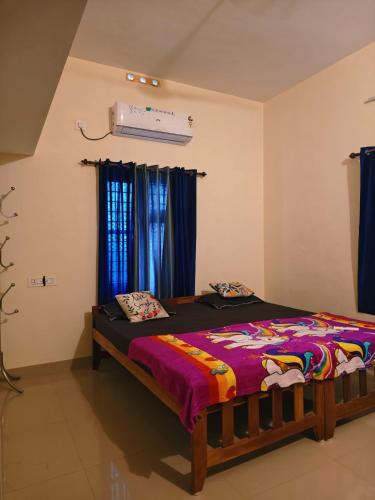 a bedroom with a bed in a room with blue curtains at Phoenix homestay in Varkala