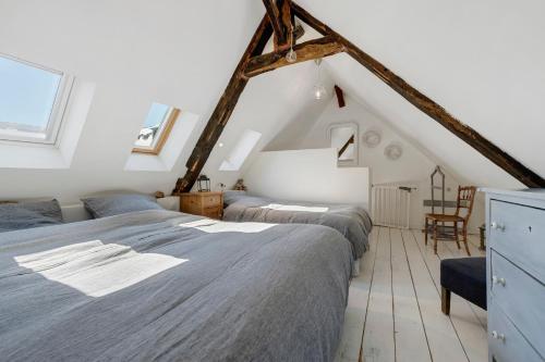 a attic bedroom with two beds and a chair at La maisonette Ti Arzou in Le Conquet