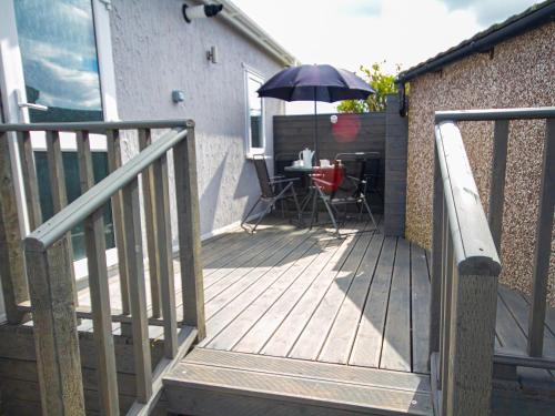 a wooden deck with a table and an umbrella at Lazy Daize in Saint Merryn