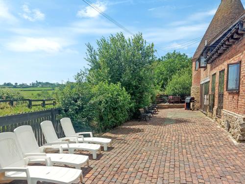 a row of white chairs sitting on a brick walkway at Thornsdale Oast House in Stone