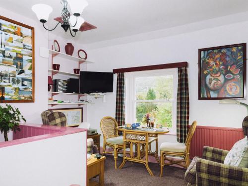 a living room with a table and chairs and a window at Tŷ Melindwr in Capel Bangor